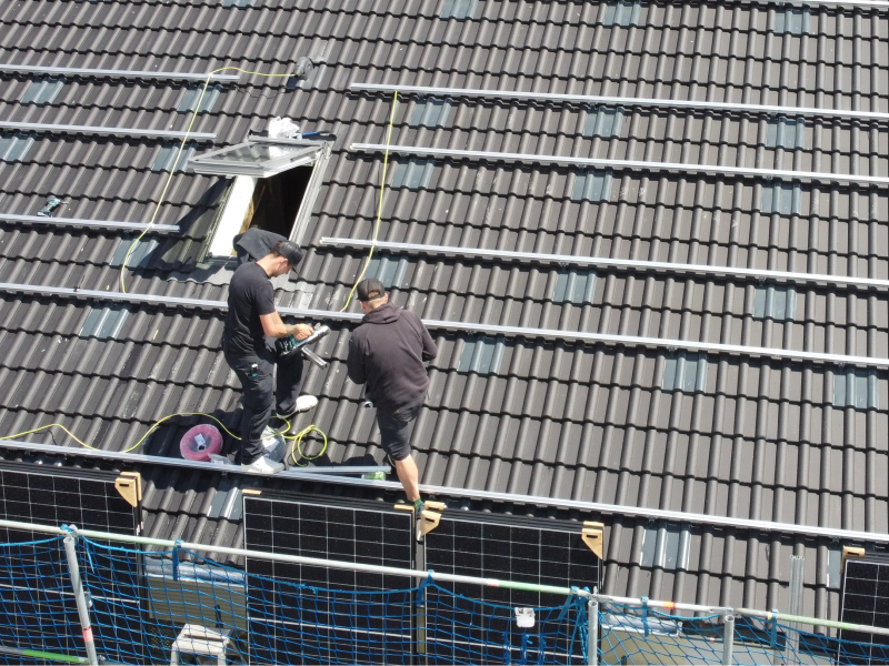 Zwei Mitarbeiter von Mahn Servicetechnik installieren eine Solaranlage auf einem Dach.